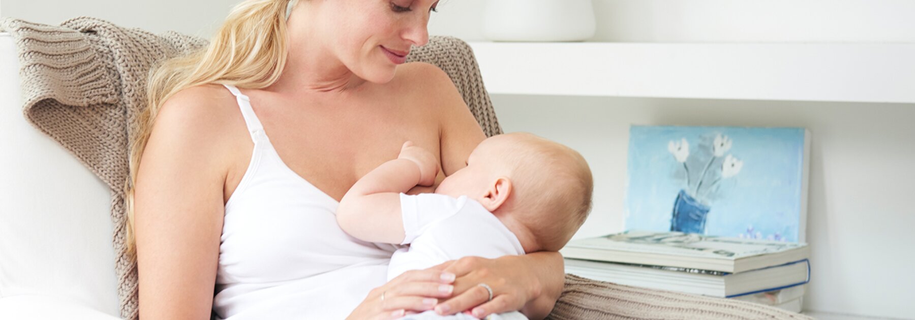 A mom is sitting on the chair at home breastfeeding her baby.