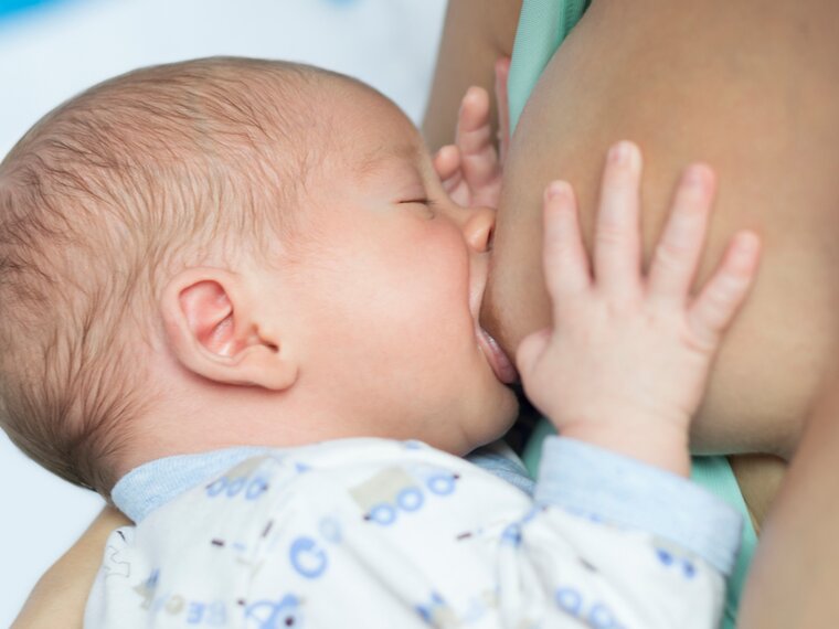 Baby drinking breast milk directly from mother's breast during breastfeeding session