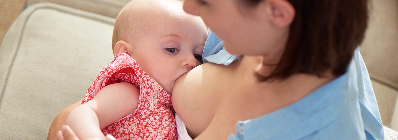 Una madre è a casa e allatta il suo bambino.