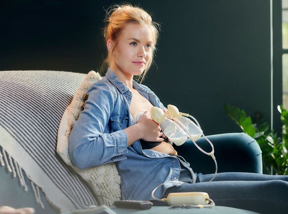 A mother pumping with a Medela Freestyle Flex™ Two-phase double electric breast pump while sitting at home.