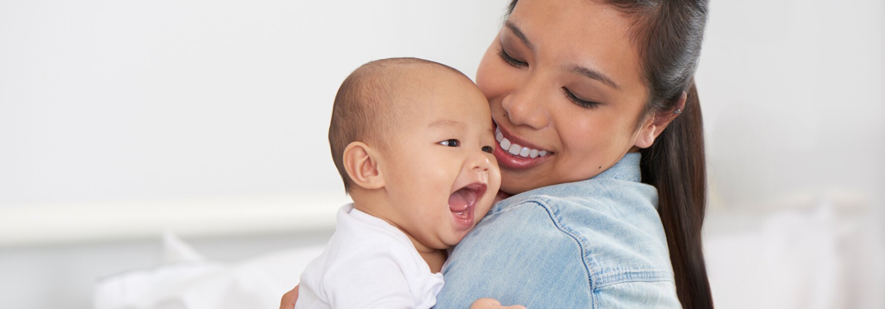 A mom holds her happy baby and smiles.
