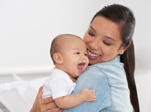 A mom holds her happy baby and smiles.