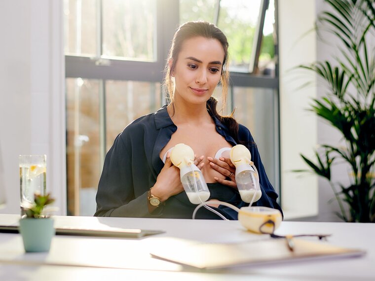 A mother using a Medela Freestyle™ Hands-free electric double breast pump at work.