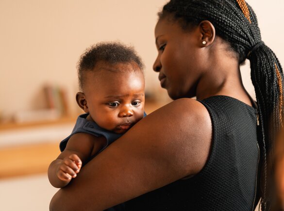 A mom holds her baby in her arms at home.