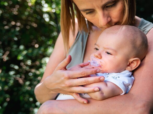 Une mère réconforte son bébé alors qu'ils sont assis à l'extérieur.