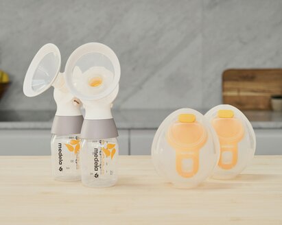 Un set di coppette Medela Hands-free Collection con un kit di pompaggio doppio Medela classic PersonalFit Flex™, tubi non mostrati, appoggiato su un bancone.
