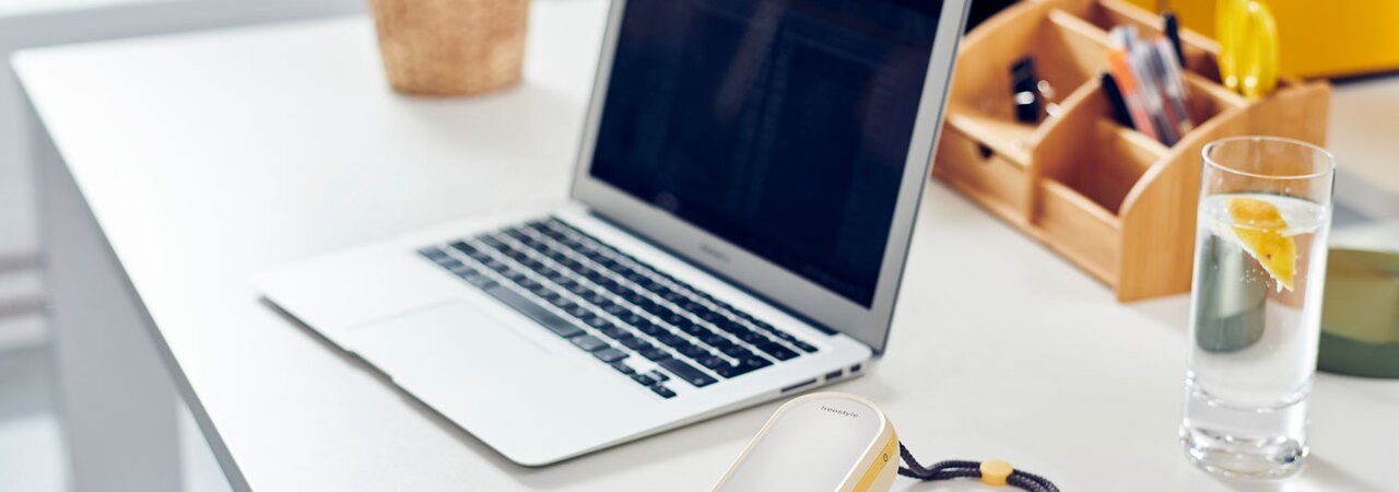 A Freestyle Flex™ double electric 2-phase breast pump on the desk next to a laptop.