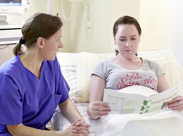 Eine Krankenschwester gibt einer Mutter Informationen über Mastitis.