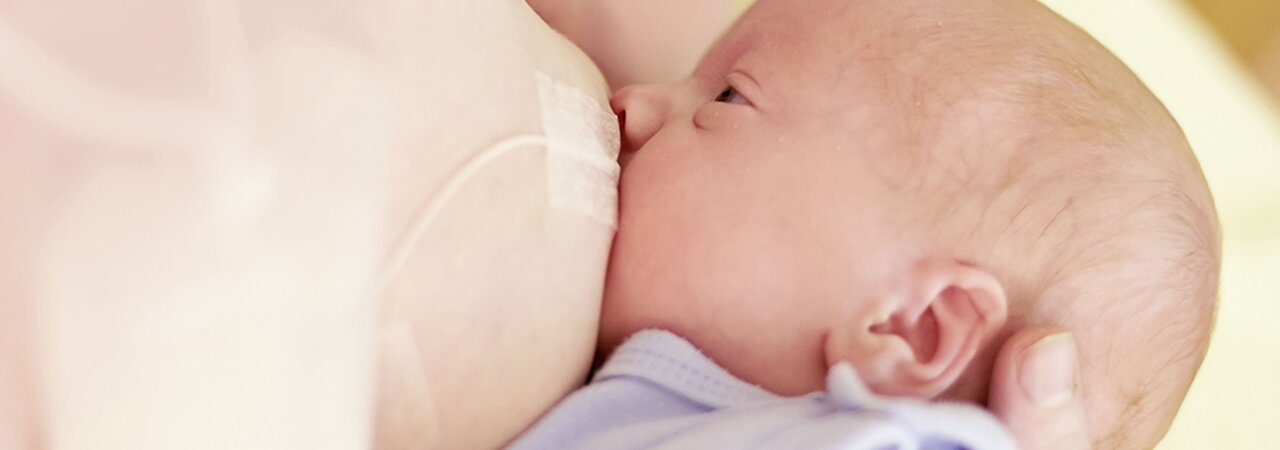 Una mamá amamanta a su bebé y complementa la dieta utilizando el Supplemental Nursing System™ (SNS) de Medela.