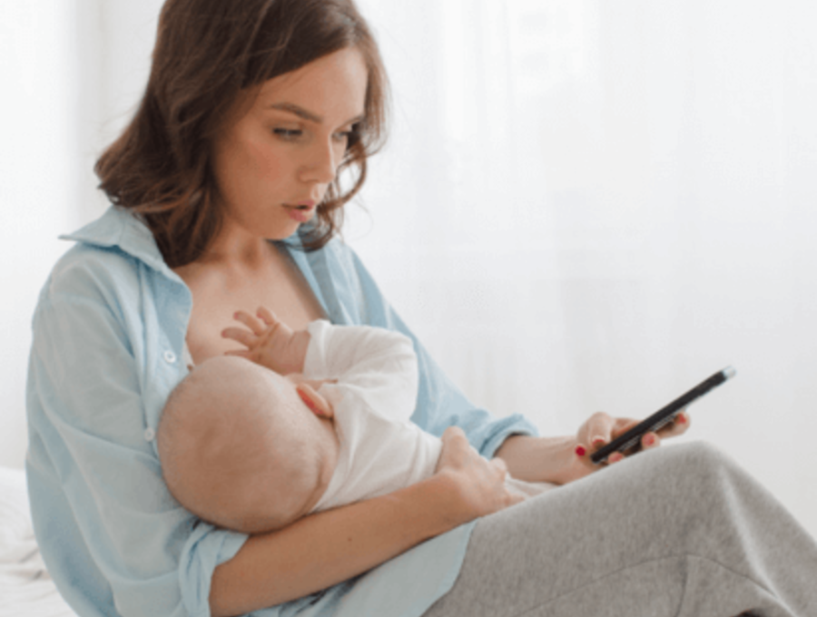 Mom looking at her phone while breastfeeding her baby.